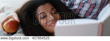 Portrait Of Latino American Young Woman Reading Interesting Book Laying On Fathers Lap. Smiling Fema