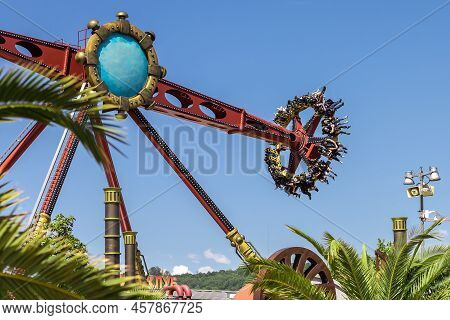 Russia, Sochi 14.05.2022. A Giant Spinning Amusement Ride In South Park Takes People Over Palm Trees