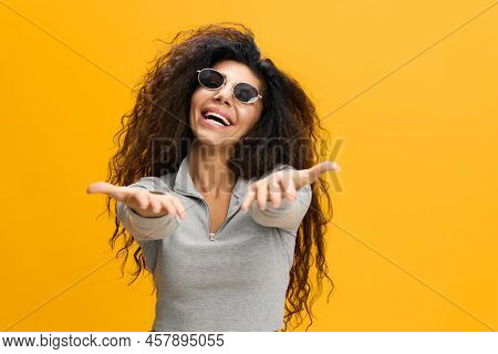 Come To Me. Excited Latin Lady Extending Hands At Camera, Holding Big Invisible Oblect, Arab Woman O