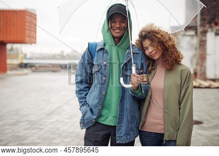 Prettyy Teenage Girl Keeping Head On Shoulder Of Her Happy Boyfriend While Both Standing Under Umbre