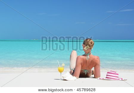 Dívka se sklenicí pomerančového džusu na pláži Exuma, Bahamy