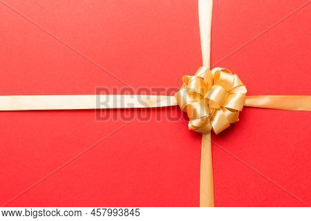 Top View Of Gold Ribbon Rolled And Yellowbow Isolated On Colored Background. Flat Lay With Copy Spac