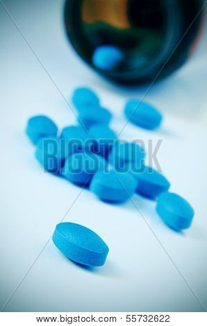 a pile of blue pills coming out of a bottle