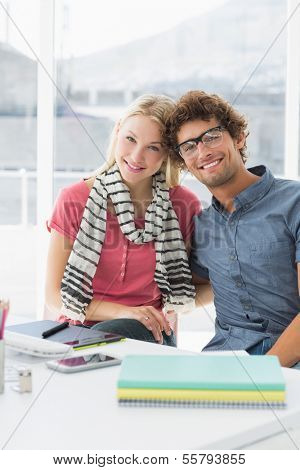 Portrait of a smiling casual business couple sitting in a bright office