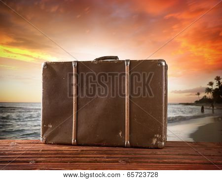 Concept of summer travelling with old suitcase. Blur beach on background
