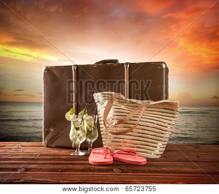 Concept of summer travelling with old suitcase and accessories. Blur beach on background