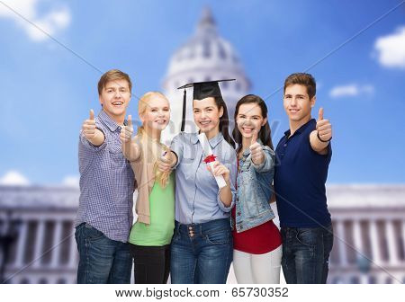 education and people concept - group of standing smiling students with diploma and corner-cap showing thumbs up