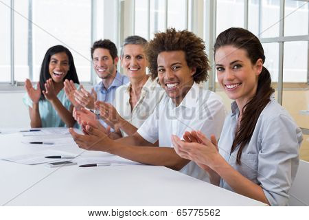 Business people clapping and smiling at camera in the office