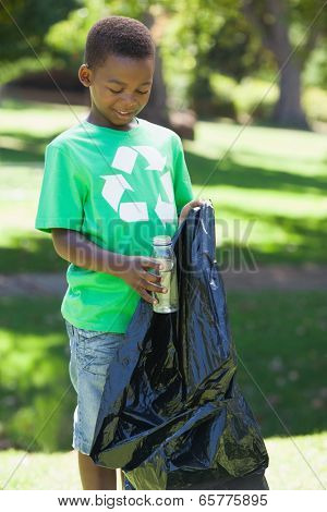 Young boy in recycling tshirt picking up trash on a sunny day