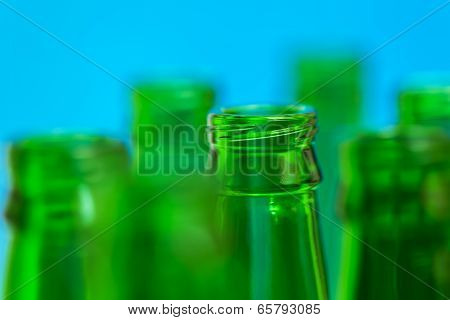 Seven Green Bottle Necks On Blue Background.