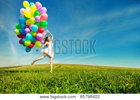 Happy birthday woman against the sky with rainbow-colored air balloons in hands. sunny and positive energy of nature. Young beautiful girl on the grass in the park.