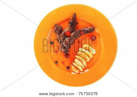 grilled beef meat with berries fried potatoes and cherry under sweet honey sauce on orange plate isolated over white background high resolution hidef