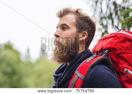 adventure, travel, tourism, hike and people concept - smiling man with beard and red backpack hiking