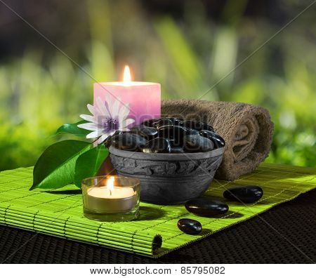 jar of black stones and candles on green mat