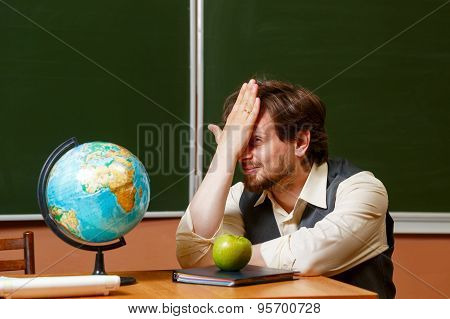 Geography Teacher Sits In Front Of A Globe.