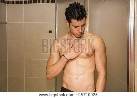 Muscular fit young man applying ointment to his chest