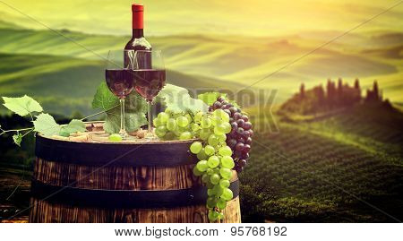 Red wine bottle and wine glass on wodden barrel. Beautiful Tuscany background