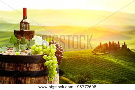 Red wine with barrel on vineyard in green Tuscany, Italy