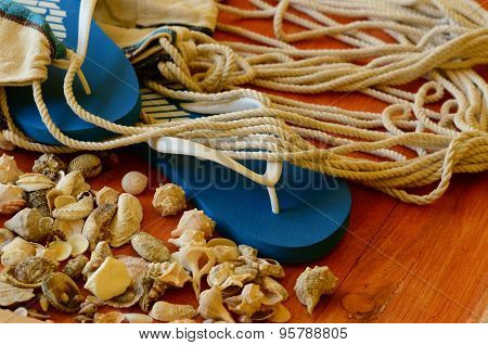 Flip-flops, shells and hammock net on wooden background