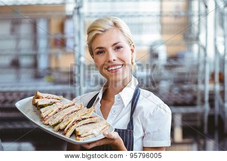 Selfassured female cook smiling holding sandwiches