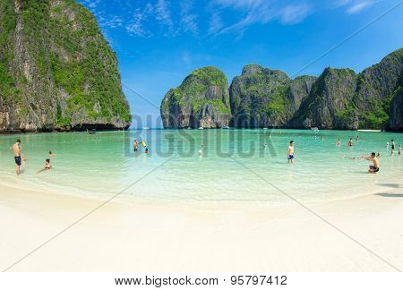    MAYA BAY, THAILAND - FEBRUARY 24, 2012: Visitors wade into the bright blue shallows of Maya Bay, one of the iconic beaches of Southern Thailand.