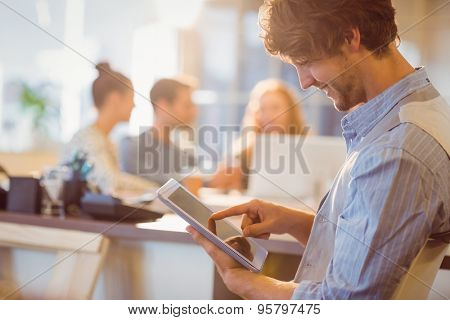 Smiling young man using digital tablet in the office