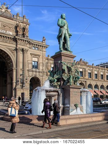 Zurich, Switzerland - 27 January, 2017: people taking pictures of the frozen fountain at the basement of the monument to Alfred Escher on Bahnhofplatz square. Temperatures in Zurich during January of 2017 were unusually low.