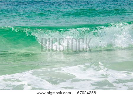 Warm tropical ocean beach waves splashing onto sea side shoreline.  Scenic travel destination location.  Blue green waters crashing ashore.