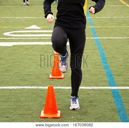 A runner is performing a running drill over orange cones