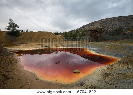 Lake with red polluted toxic water of an Abandoned copper mine at Mitsero area in Cyprus