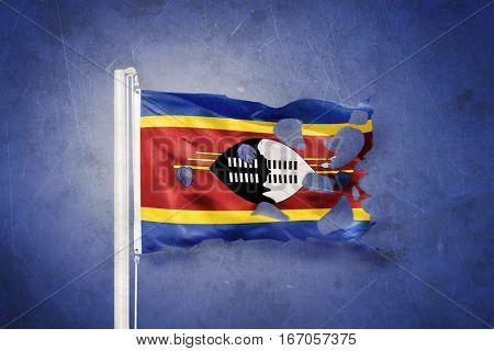 Torn flag of Swaziland flying against grunge background