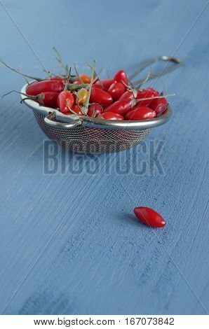 fresh undried goji berries in front of a blue wooden background