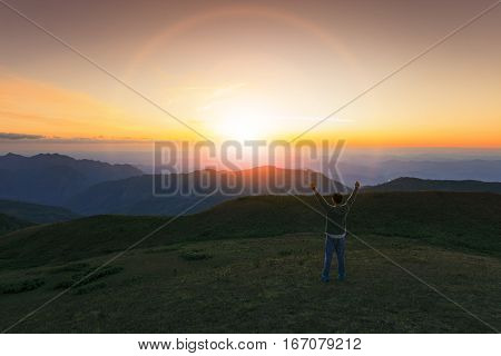 traveling man rising victory hand with succsessful and freedom feeling on high mountain against beautiful sun set sky