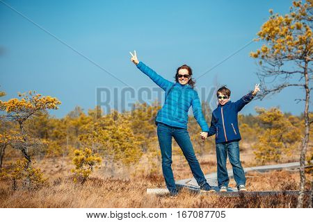 Cute little boy with his mother walking on trail in swamp and having fun, Kemeri national park, Latvia