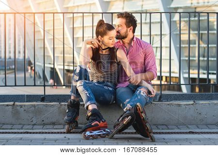 Couple on rollerblades sitting. Two people in the street. Time spent together is priceless.