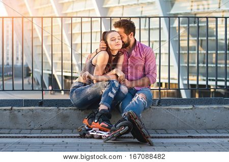 Couple of inline skaters sitting. Young woman with closed eyes. Fall in love.