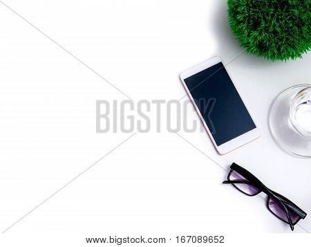 Minimal white office desk table  glass of drinking water and flower pot. Top view with copy space, flat lay.