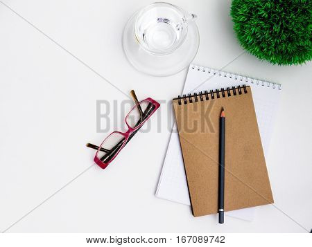 Minimal white office desk table  glass of drinking water and flower pot. Top view with copy space, flat lay.