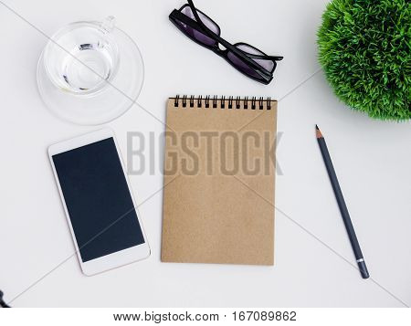 Minimal white office desk table  glass of drinking water and flower pot. Top view with copy space, flat lay.