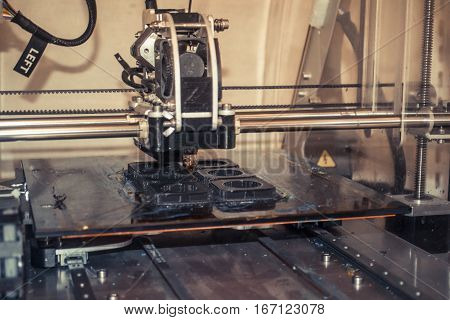 Modern 3D printer printing figure close-up macro. Automatic three dimensional 3d printer performs plastic modeling in laboratory.