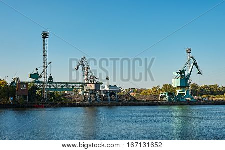 cranes on the quay of the river under blue sky