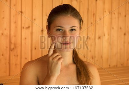 young nude blond woman in wooden sauna