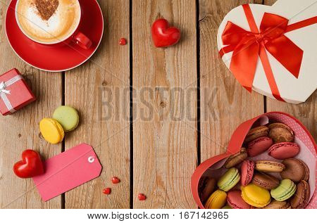 Valentines day concept with macarons coffee cup and gift box over wooden background. Top view from above