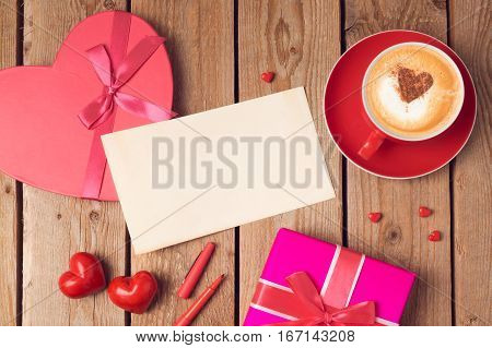 Valentines day concept with greeting card gift box and coffee cup over wooden background. Top view from above