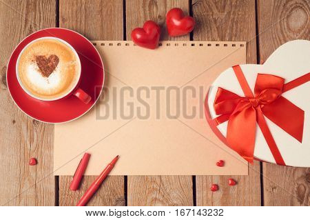 Valentines day concept with greeting card gift box and coffee cup over wooden background. Top view from above