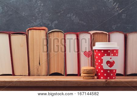 Valentines day concept with paper coffee cup macarons and vintage books on wooden table