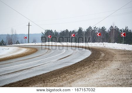 The road with dirty snow and signs in the daytime