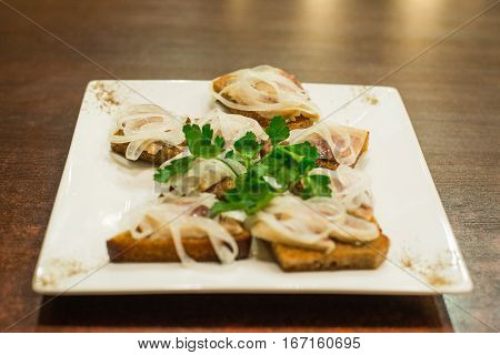 Toasts with herring and onion decorated with parsley