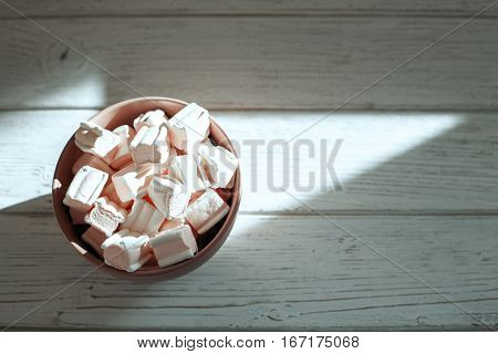 Marshmellow in a bowl on a wooden background. Top view. The concept of food.