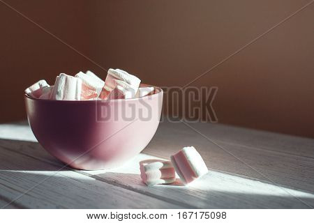 Marshmellow in a bowl on a white table. The concept of food.